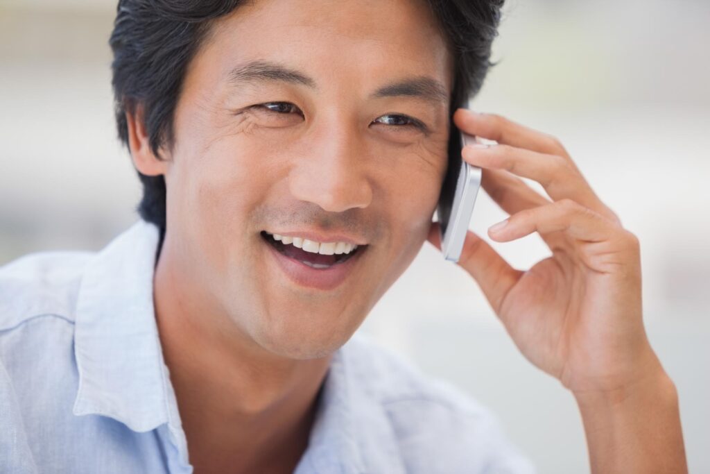 a man smiles while talking on a cell phone